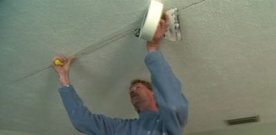 Using selfadhesive fiberglass mesh tape to repair a ceiling crack.