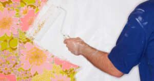 man painting over wallpaper