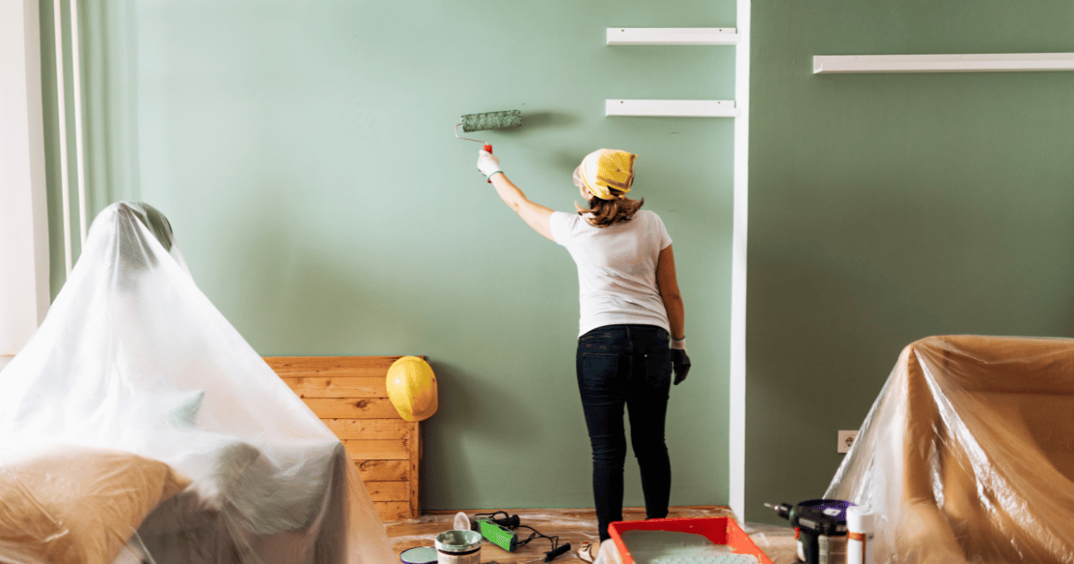 woman painting a wall green