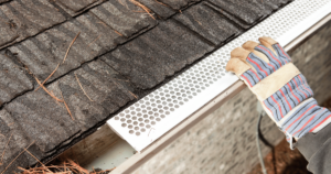 gloved hand performing gutter guard installation